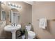 Cozy bathroom with pedestal sink, decorative mirror, and a toilet at 7460 Grassy Field Ct, Las Vegas, NV 89131