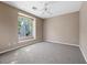 A bright bedroom featuring a large window, plush carpeting, and a modern ceiling fan at 7460 Grassy Field Ct, Las Vegas, NV 89131