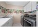 Well-equipped laundry room with stainless steel washer and dryer set and a sink with bright wallpaper at 7460 Grassy Field Ct, Las Vegas, NV 89131