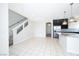 Open-concept living room and kitchen featuring tile flooring, stainless steel appliances and a staircase with white rails at 8276 Sorrel St, Las Vegas, NV 89139