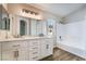Bright bathroom with double vanity, white cabinetry, tub-shower combination, and wood-look flooring at 844 Binbrook Dr, Henderson, NV 89052