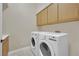 Convenient laundry room with upper cabinets and modern washer and dryer at 8945 S Tenaya Way, Las Vegas, NV 89113