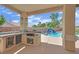 Covered outdoor kitchen with a sink, built-in grill, and easy access to the pool and patio at 8945 S Tenaya Way, Las Vegas, NV 89113