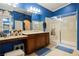 Well-lit bathroom featuring a double vanity, shower, and blue walls with decorative accents at 9373 Oxbow Lake Ave, Las Vegas, NV 89149