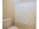 Close up on the white toilet and shower with leaf-patterned curtain in the bathroom at 9373 Oxbow Lake Ave, Las Vegas, NV 89149