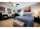 Comfortable bedroom featuring a blue striped duvet, ceiling fan, and various vintage automotive art at 9373 Oxbow Lake Ave, Las Vegas, NV 89149