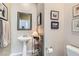 Cozy powder room featuring a pedestal sink, decorative mirror, and elegant wall art at 939 Paisley St, Las Vegas, NV 89145