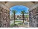 Balcony view framed by a stone archway showcasing palm trees and neighborhood at 9504 Empire Rock St, Las Vegas, NV 89143