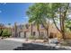 Exterior shot of a townhouse complex with stucco facade, arched windows, and mature trees at 9655 Lame Horse Dr, Las Vegas, NV 89123