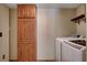 A tall wood cabinet and modern washer/dryer in the laundry area with tile flooring at 9655 Lame Horse Dr, Las Vegas, NV 89123