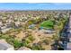 Expansive aerial view of neighborhood highlighting park with shade structures, lush trees, walking trails, and desert landscape at 9831 Running Rabbit St, Las Vegas, NV 89143