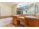 Bathroom featuring double sinks, bathtub, and a window for natural lighting at 10457 Armand Ave, Las Vegas, NV 89129