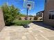 Spacious backyard with a basketball hoop on a paved patio and green lawn at 10650 Robin Hill Ave, Las Vegas, NV 89129