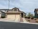 Two-story home featuring a three car garage, steps leading to the front door, and desert landscaping at 10650 Robin Hill Ave, Las Vegas, NV 89129