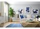 Bright living room with hardwood floors, a comfortable sofa, stylish artwork, and a large fiddle leaf fig tree at 1212 Crimson Sunbird St, North Las Vegas, NV 89084