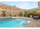 Beautiful backyard with a sparkling pool, spa, outdoor seating, and a lush rock wall at 21 Grand Masters Dr, Las Vegas, NV 89141