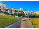 Exterior shot of the grand clubhouse with meticulous landscaping and a row of golf carts, and blue sky at 21 Grand Masters Dr, Las Vegas, NV 89141
