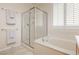 Bright bathroom featuring a tub and shower, window with plantation shutters, and neutral colored towels at 2163 Bannerwood St, Henderson, NV 89044
