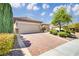 Inviting single-story home boasts a brick driveway leading to a two-car garage and lush front yard at 2163 Bannerwood St, Henderson, NV 89044