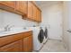 Laundry room with upper cabinets, sink, countertop and a white front loading washer and dryer at 2163 Bannerwood St, Henderson, NV 89044