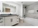 Modern bathroom featuring custom vanity, black hardware, tiled shower, and large, lighted mirror at 2528 Sunup Dr, Las Vegas, NV 89134