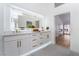 Bright bathroom with illuminated mirrors, double sinks, and white cabinetry with gold hardware, offering a spa-like experience at 2528 Sunup Dr, Las Vegas, NV 89134