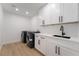 Well-lit laundry room features white cabinets, quartz countertop, black hardware, and modern machines at 2528 Sunup Dr, Las Vegas, NV 89134
