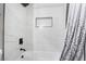 Updated bathroom features a shower-tub combo, accented with black fixtures and sleek white tiling at 4786 San Rafael Ave, Las Vegas, NV 89120
