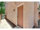 Side view of a peach stucco home featuring a solid front door with detailed trim and a walkway at 5588 Ness Ave, Las Vegas, NV 89118