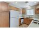 A functional kitchen featuring wooden cabinets, white appliances, and tile flooring at 5588 Ness Ave, Las Vegas, NV 89118