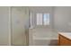 Bathroom featuring a window, frosted glass shower door and a built in tub at 6424 Bombax Ct, Las Vegas, NV 89141