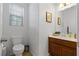 This bathroom has a single sink vanity with wood base, framed art and a window letting in natural light at 7237 Puddle Duck St, Las Vegas, NV 89166
