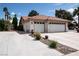 Exterior view of a three car garage with a large driveway and minimal landscaping at 7660 Descanso Ln, Las Vegas, NV 89123