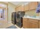 Well-organized laundry room features modern washer and dryer, sink and storage cabinets at 884 Loma Bonita Pl, Las Vegas, NV 89138
