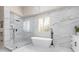 Modern bathroom featuring a soaking tub, glass enclosed shower, and white marble tile at 9 Chalet Hills Ter, Henderson, NV 89052