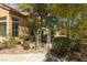 Exterior view of the home showcasing the beautiful landscaping, including mature trees, bushes and a charming white arbor at 9 Chalet Hills Ter, Henderson, NV 89052