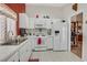Traditional kitchen featuring white appliances, cabinets, and tile flooring with a window and an adjacent doorway to a room at 1658 Autumn Rust Dr, Las Vegas, NV 89119