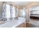 Bright bathroom featuring a soaking tub, a glass-enclosed shower, and floral curtains at 4708 Grand Rock Dr, North Las Vegas, NV 89081