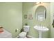 Compact half-bathroom with pedestal sink, toilet, and decorative wall art at 5300 E La Terra Ave, Pahrump, NV 89061