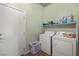 Functional laundry room with white washer, dryer, storage shelves, and a large utility sink at 5300 E La Terra Ave, Pahrump, NV 89061