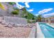 A well-manicured backyard featuring a pool with a retaining wall, beautiful landscaping, and a clear blue sky at 1862 Redwood Valley St, Henderson, NV 89052