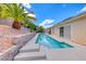 Tropical backyard featuring a pool with a retaining wall, lush greenery, palm trees, and desert landscaping at 1862 Redwood Valley St, Henderson, NV 89052