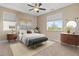 This bedroom features a light grey bed with stylish decorations, large windows and a ceiling fan at 4212 Hawks Glide Ave, North Las Vegas, NV 89084