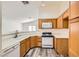 Well-maintained kitchen with wood cabinets, white appliances, and a pass-through to the dining area at 5114 Mascaro Dr, Las Vegas, NV 89122