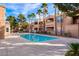 Community pool with tan apartment buildings and palm trees under a partly cloudy sky at 8101 W Flamingo Rd # 2059, Las Vegas, NV 89147
