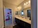 Well-lit bathroom with dual sinks, granite countertops, a large mirror, and a view into the pink bedroom at 8303 Saddleback Ledge Ave, Las Vegas, NV 89147