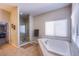 Serene bathroom with a soaking tub, separate glass-enclosed shower, and neutral tile flooring, creating a spa-like experience at 8303 Saddleback Ledge Ave, Las Vegas, NV 89147