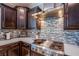 Close-up of the kitchen featuring dark wood cabinetry, modern backsplash, and stainless steel appliances at 8303 Saddleback Ledge Ave, Las Vegas, NV 89147