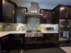 Modern kitchen features dark wood cabinets, stainless steel appliances, and mosaic tile backsplash at 8303 Saddleback Ledge Ave, Las Vegas, NV 89147
