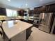 Open kitchen with white countertops, dark cabinetry, stainless appliances, and center island with seating at 8303 Saddleback Ledge Ave, Las Vegas, NV 89147